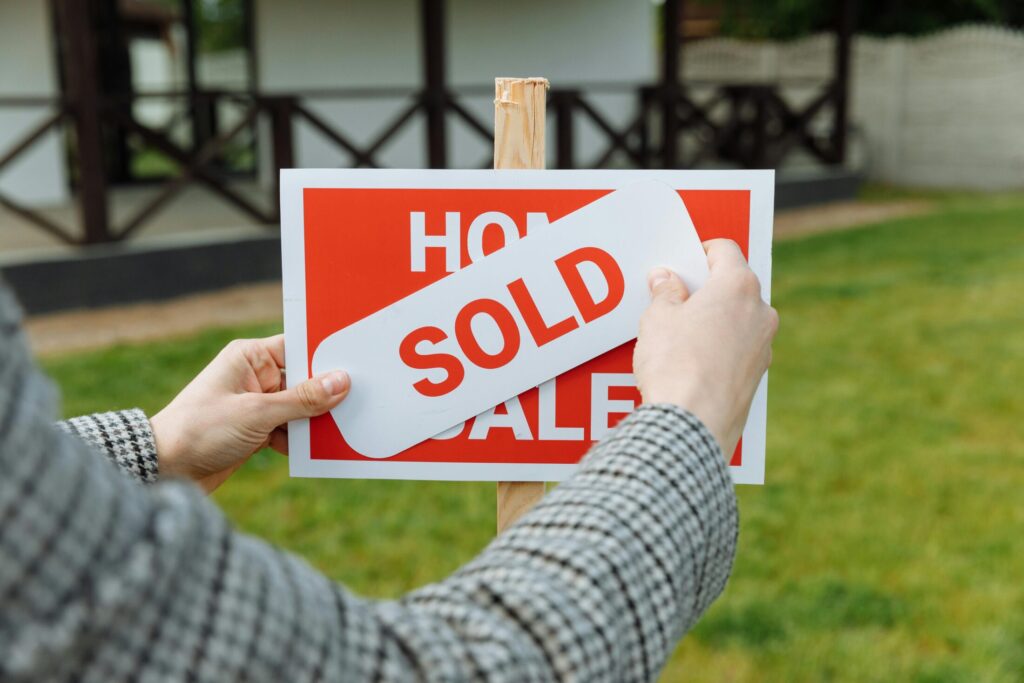 a realtor posting a sold sticker to a for sale sign